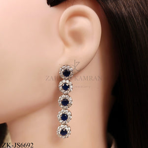 Elegant designer necklace and earring set featuring sparkling sapphire  surrounded by zirconia in a silver metal finish.