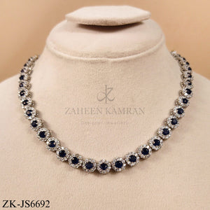 Elegant designer necklace and earring set featuring sparkling sapphire  surrounded by zirconia in a silver metal finish.